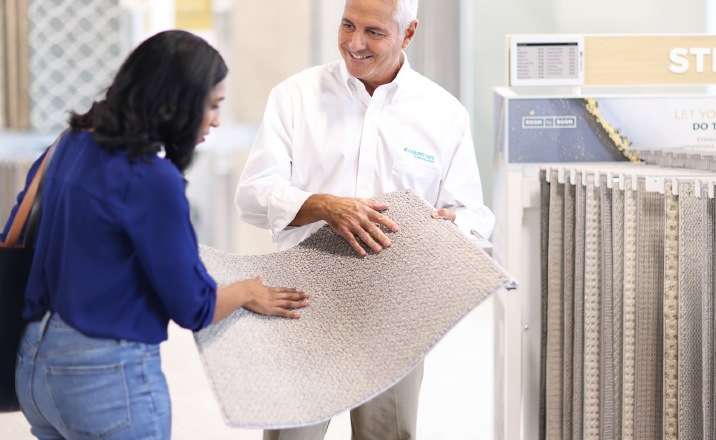 flooring expert showing customer carpet flooring sample in flooring showroom