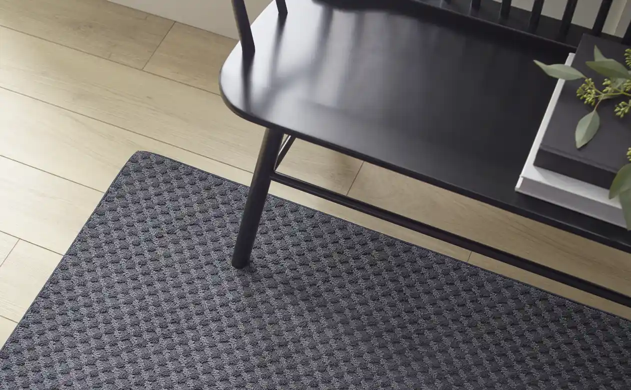 dark grey area rug in hallway with wooden bench